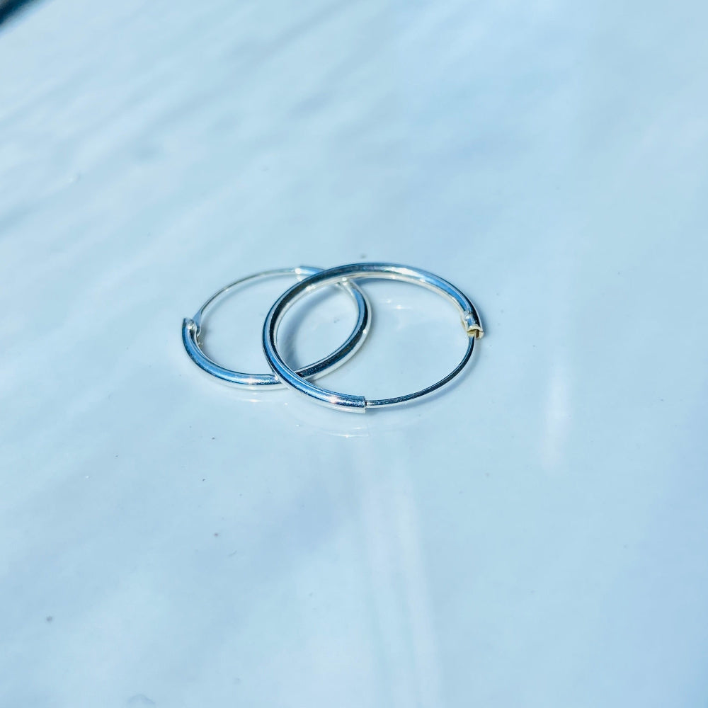 Two silver rings on a light blue fabric surface silver sleeper hoop earrings for king queen womens mens 925 silver sterling silver exclusive Deep Shine Jewellers jewellery jewelry Your Time To Shine shop now DSJ affordable luxury high quality