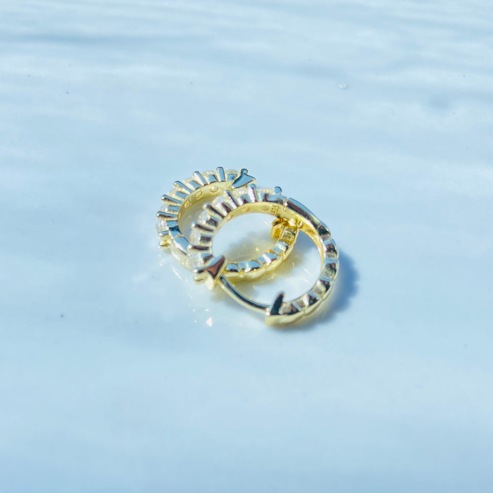 Gold ring with embedded stones on a light blue fabric background Gold ring with diamonds on a white box Gold silver ice sleeper hoop earring yellow gold 925 silver sterling silver womens ladies queens shine bright exclusive Deep Shine Jewellers jewellery jewelry DSJ Your Time To Shine affordable luxury trendy best beauty diamonds cubic zirconia