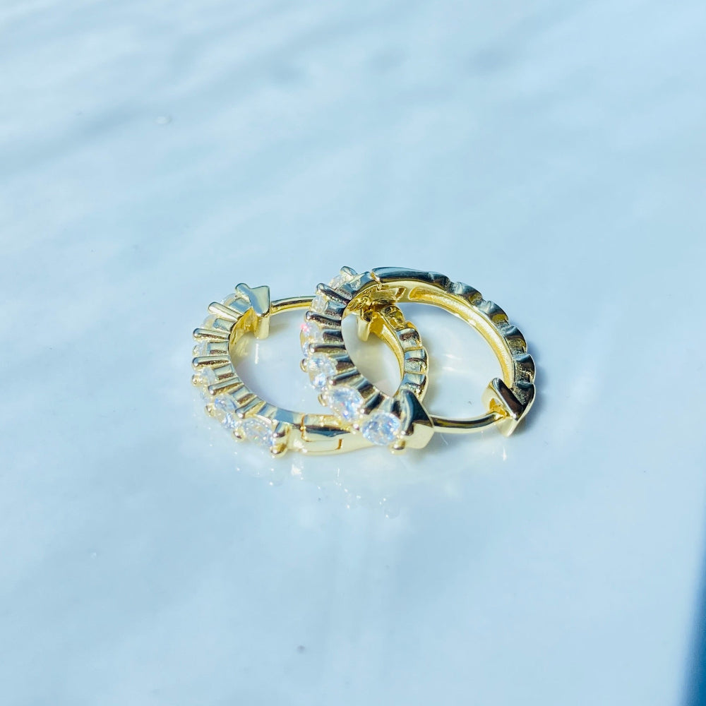 Two gold hoop earrings on a light blue fabric background Gold ring with diamonds on a white box Gold silver ice sleeper hoop earring yellow gold 925 silver sterling silver womens ladies queens shine bright exclusive Deep Shine Jewellers jewellery jewelry DSJ Your Time To Shine affordable luxury trendy best beauty  diamonds cubic zirconia