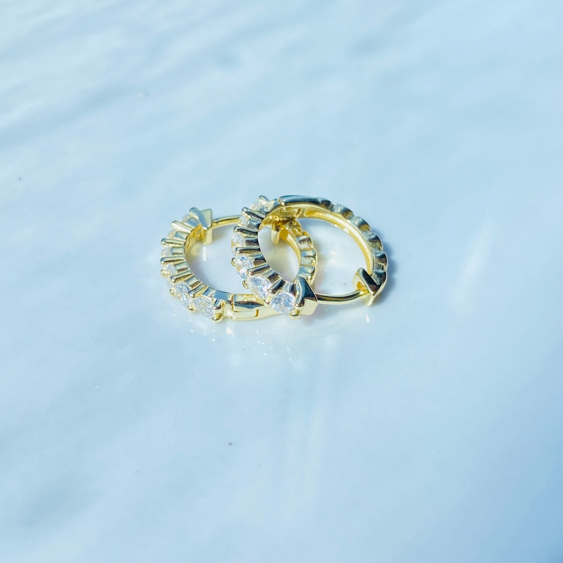 Two gold rings with gemstones on a white surface Gold ring with diamonds on a white box Gold silver ice sleeper hoop earring yellow gold 925 silver sterling silver womens ladies queens shine bright exclusive Deep Shine Jewellers jewellery jewelry DSJ Your Time To Shine affordable luxury trendy best beauty diamonds cubic zirconia