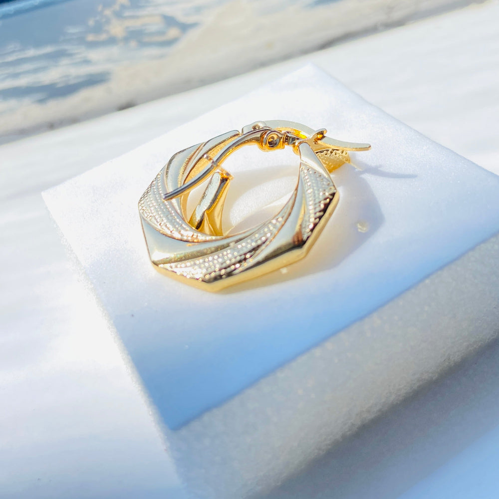 Gold ring with interlocking design on a light blue jewelry box. Gold Detailed Octagon Earrings jewellery jewelry stainless steel gold plated earrings queens ladies womens Deep Shine Jewellers Your Time To Shine Affordable luxury DSJ