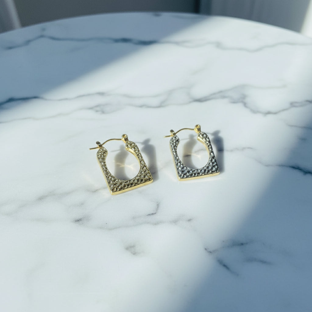 Gold hoop earrings on a light blue surface gold detailed rectangle earrings exclusive by Deep Shine Jewellers jewellery jewelry DSJ Your Time To Shine golden shine