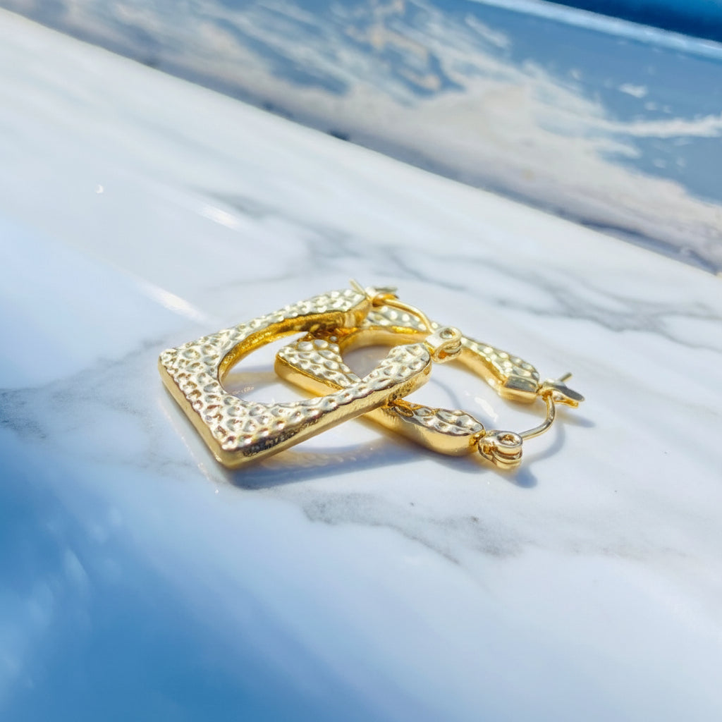 Gold hoop earrings on a light blue surface gold detailed rectangle earrings exclusive by Deep Shine Jewellers jewellery jewelry DSJ Your Time To Shine golden shine