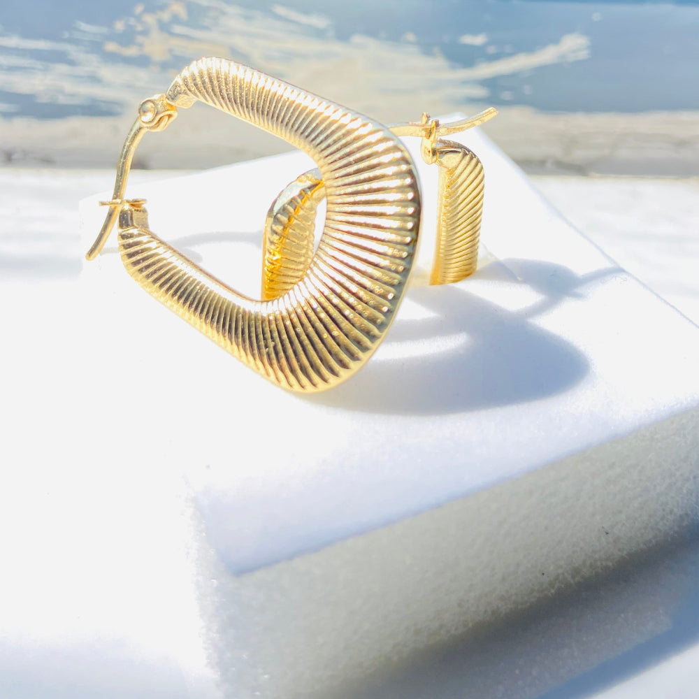 Gold hoop earrings on a white surface with a blurred outdoor background Gold striped rectangle earrings jewellery jewelry Deep Shine Jewellers stainless steel gold-plated affordable luxury DSJ Your Time To Shine exclusive radiant womens lady's queens kingdom
