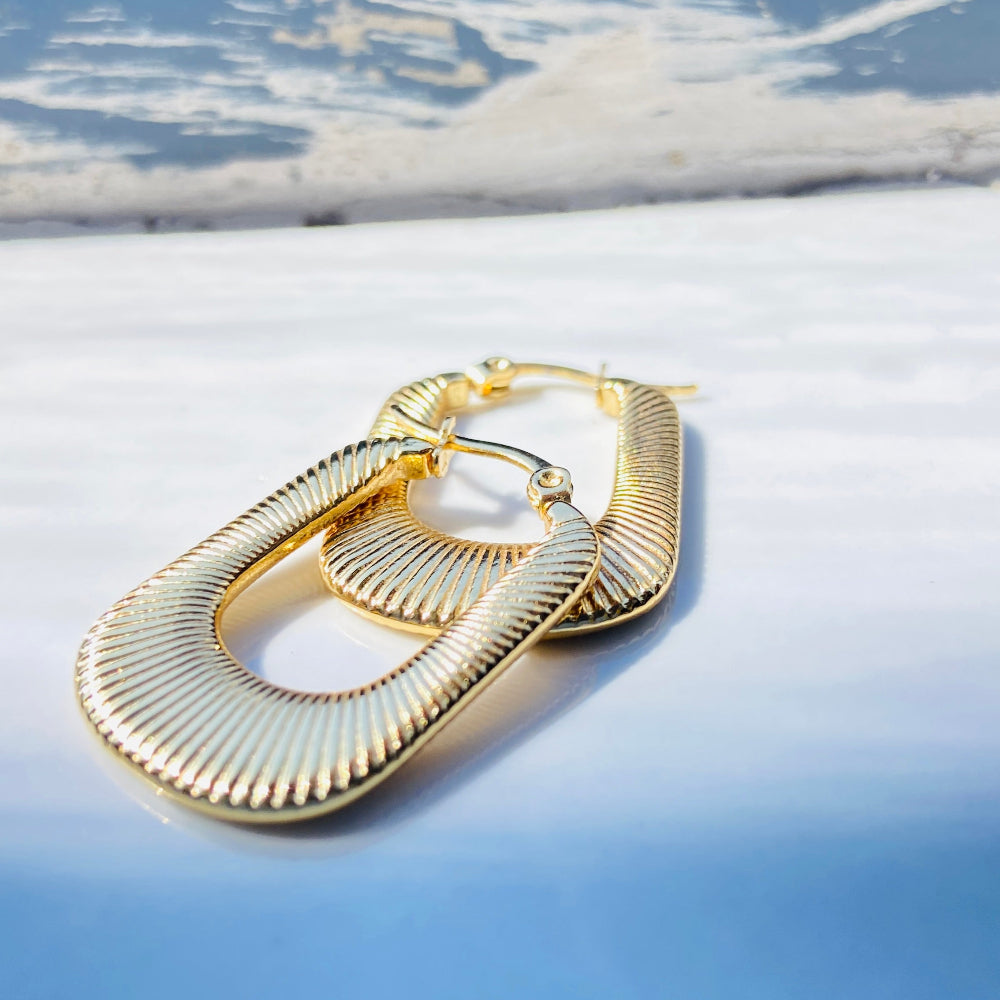 Gold hoop earrings on a light blue surface with a blurred natural background Gold striped rectangle earrings jewellery jewelry Deep Shine Jewellers stainless steel gold-plated affordable luxury DSJ Your Time To Shine exclusive radiant womens lady's queens kingdom