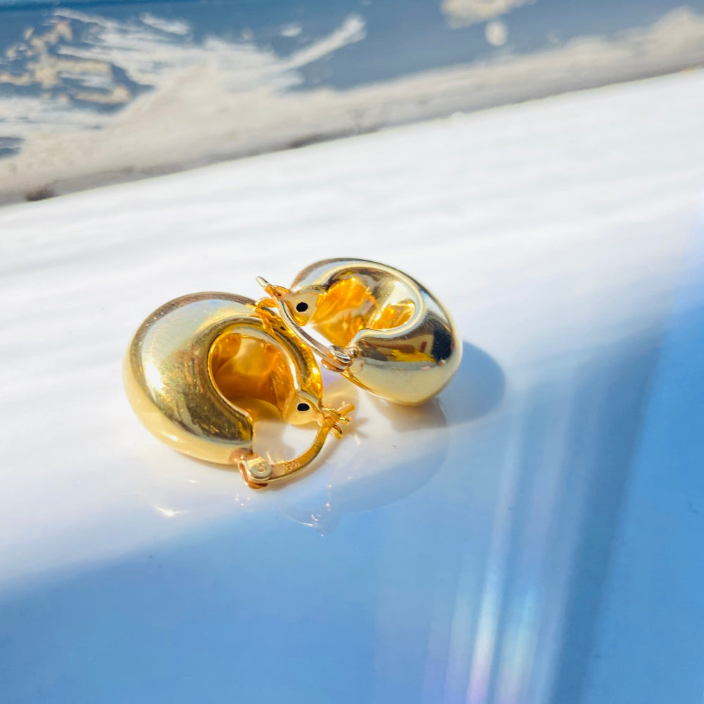 Gold heart-shaped earrings on a reflective surface with a blurred background gold silver bubble dome hoop earrings for women ladies queens exclusive craftsmanship gold 925 silver sterling silver gold-plated jewellery jewelry Deep Shine Jewellers DSJ Your Time To Shine affordable luxury beauty trendy shop now 