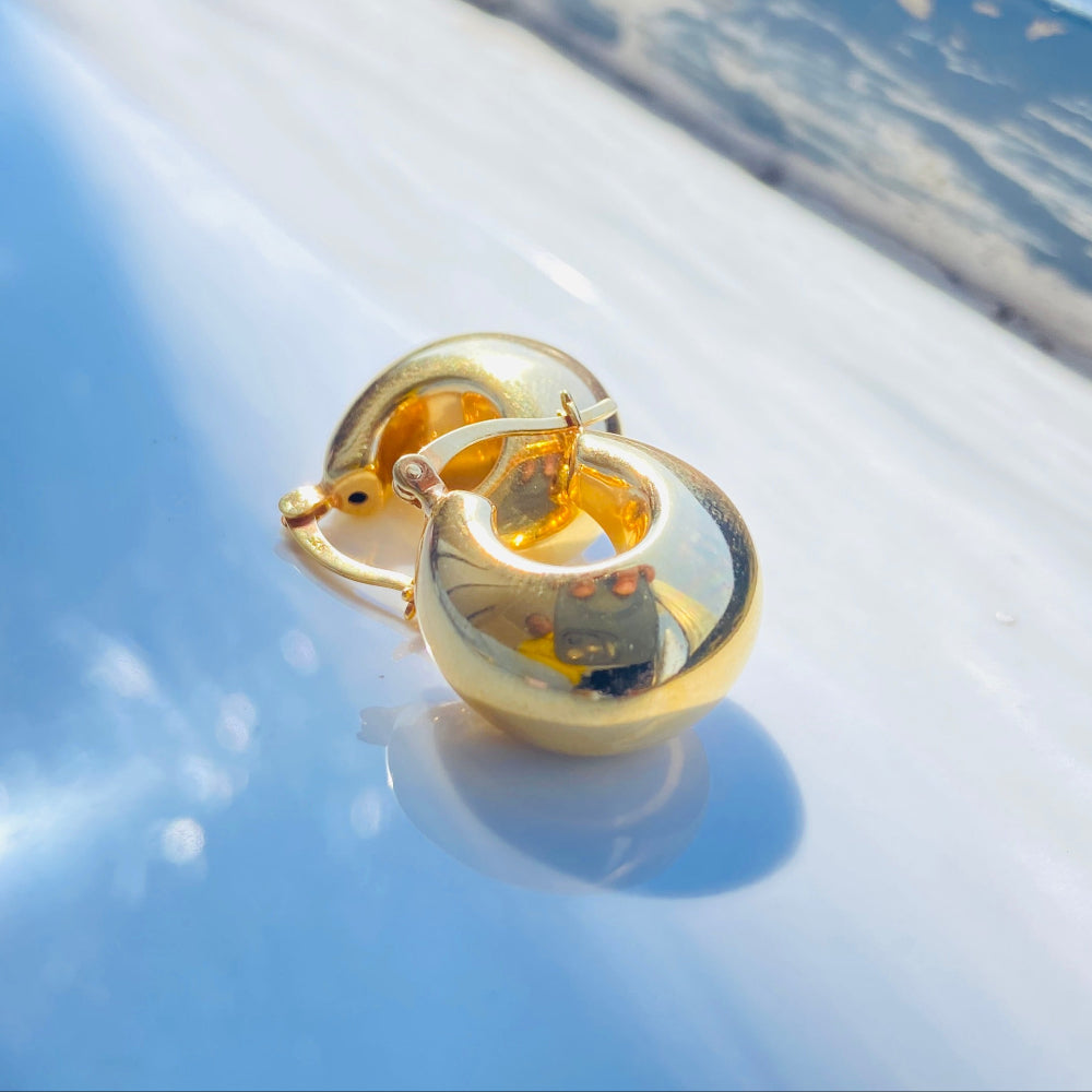 Gold earring on a reflective surface with a blurred background gold silver bubble dome hoop earrings for women ladies queens exclusive craftsmanship gold 925 silver sterling silver gold-plated jewellery jewelry Deep Shine Jewellers DSJ Your Time To Shine affordable luxury beauty trendy shop now 