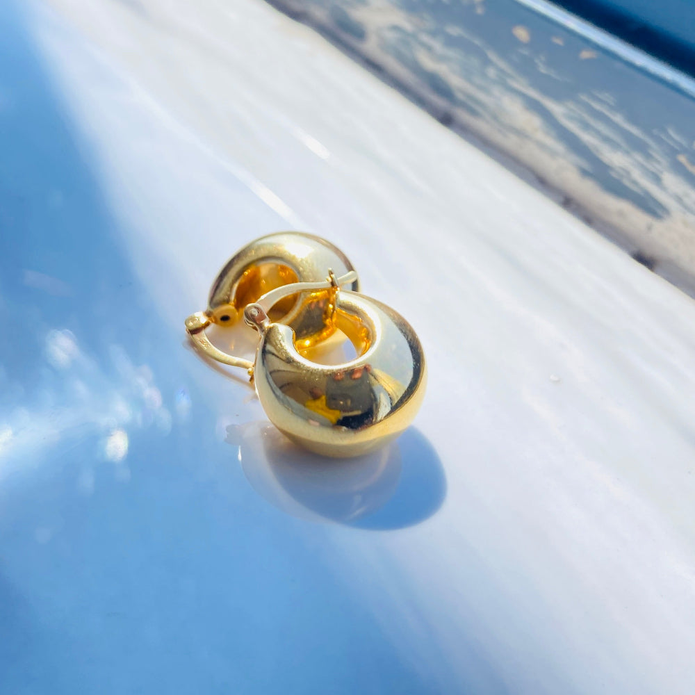 Gold earring on a reflective surface with a blurred background gold silver bubble dome hoop earrings for women ladies queens exclusive craftsmanship gold 925 silver sterling silver gold-plated jewellery jewelry Deep Shine Jewellers DSJ Your Time To Shine affordable luxury beauty trendy shop now 