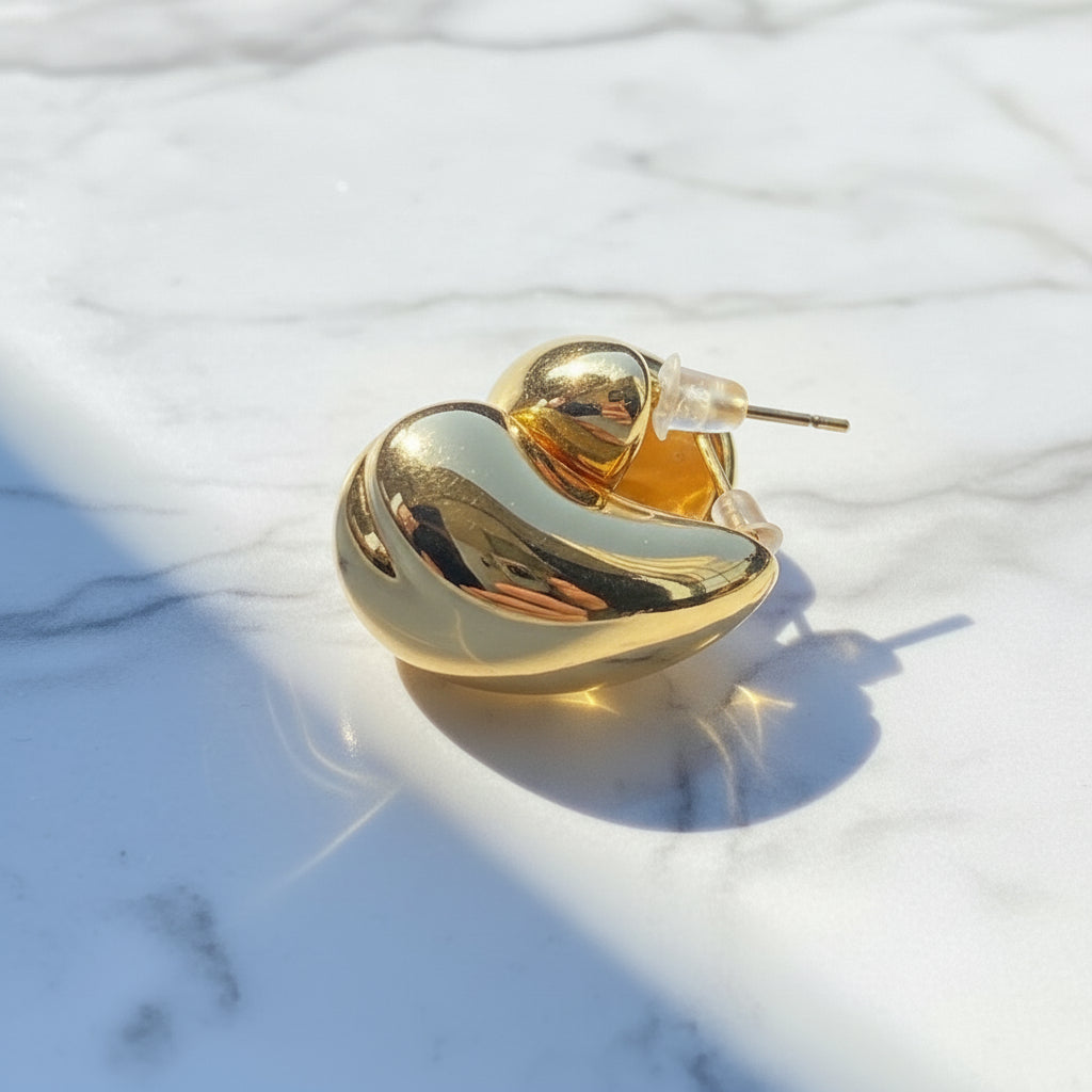 Gold ring on a white surface with a blurred natural background Gold Drop Form Earrings stainless steel female womens queens jewellery jewelry Deep Shine Jewellers Your Time To Shine DSJ affordable luxury exclusive craftsmanship