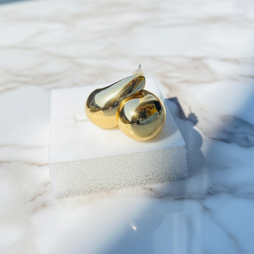 Gold ring on a white surface with a blurred natural background Gold Drop Form Earrings stainless steel female womens queens jewellery jewelry Deep Shine Jewellers Your Time To Shine DSJ affordable luxury exclusive craftsmanship
