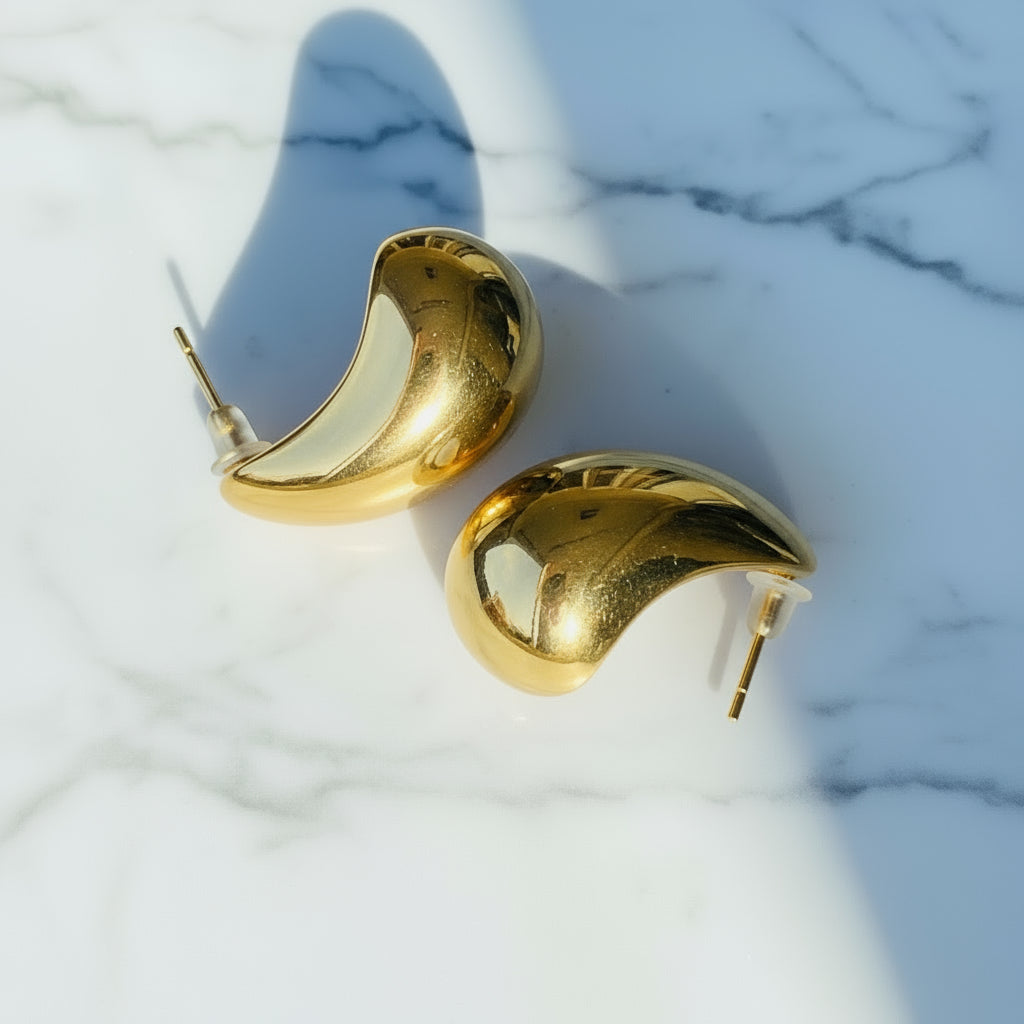 Gold earrings on a pink card with a blurred background Gold Drop Form Earrings stainless steel female womens queens jewellery jewelry Deep Shine Jewellers Your Time To Shine DSJ affordable luxury exclusive craftsmanship