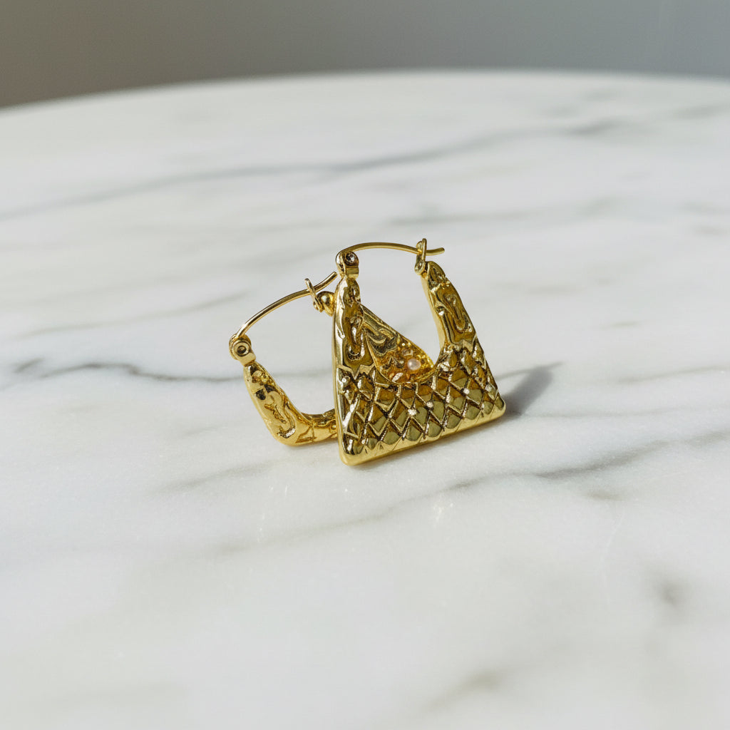 Gold hoop earrings on a white stand with a blurred background Gold crown-shaped object on a white stand with a blurred outdoor background gold crocodile design earrings stainless steel exclusive Deep Shine Jewellers DSJ jewellery jewelry Your Time To Shine queens womens ladies kingdome 