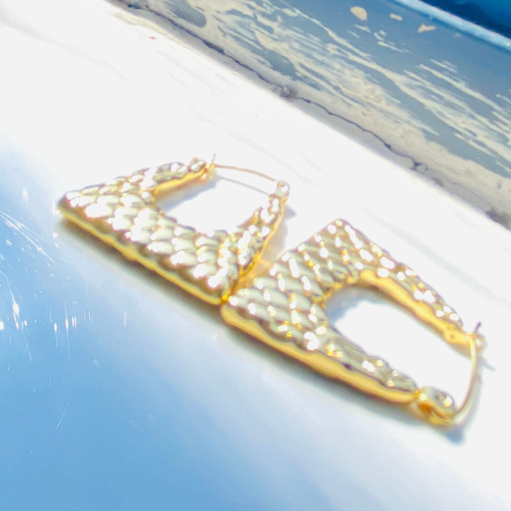 Gold and pearl earring on a reflective surface with a blue background Gold crown-shaped object on a white stand with a blurred outdoor background gold crocodile design earrings stainless steel exclusive Deep Shine Jewellers DSJ jewellery jewelry Your Time To Shine queens womens ladies kingdom