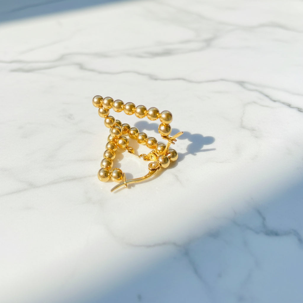 Gold beaded earrings on a blue surface stainless steel gold exclusive earrings Deep Shine Jewellers DSJ jewellery jewelry queens ladies womens kingdom Your Time To Shine