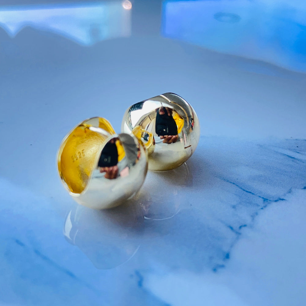 Gold earrings on a reflective surface with a blurred background gold dome silver earrings for queens ladies women 925 silver sterling silver exclusive craftsmanship Deep Shine Jewellers DSJ Your Time To Shine golden affordable luxury jewellery jewelry 