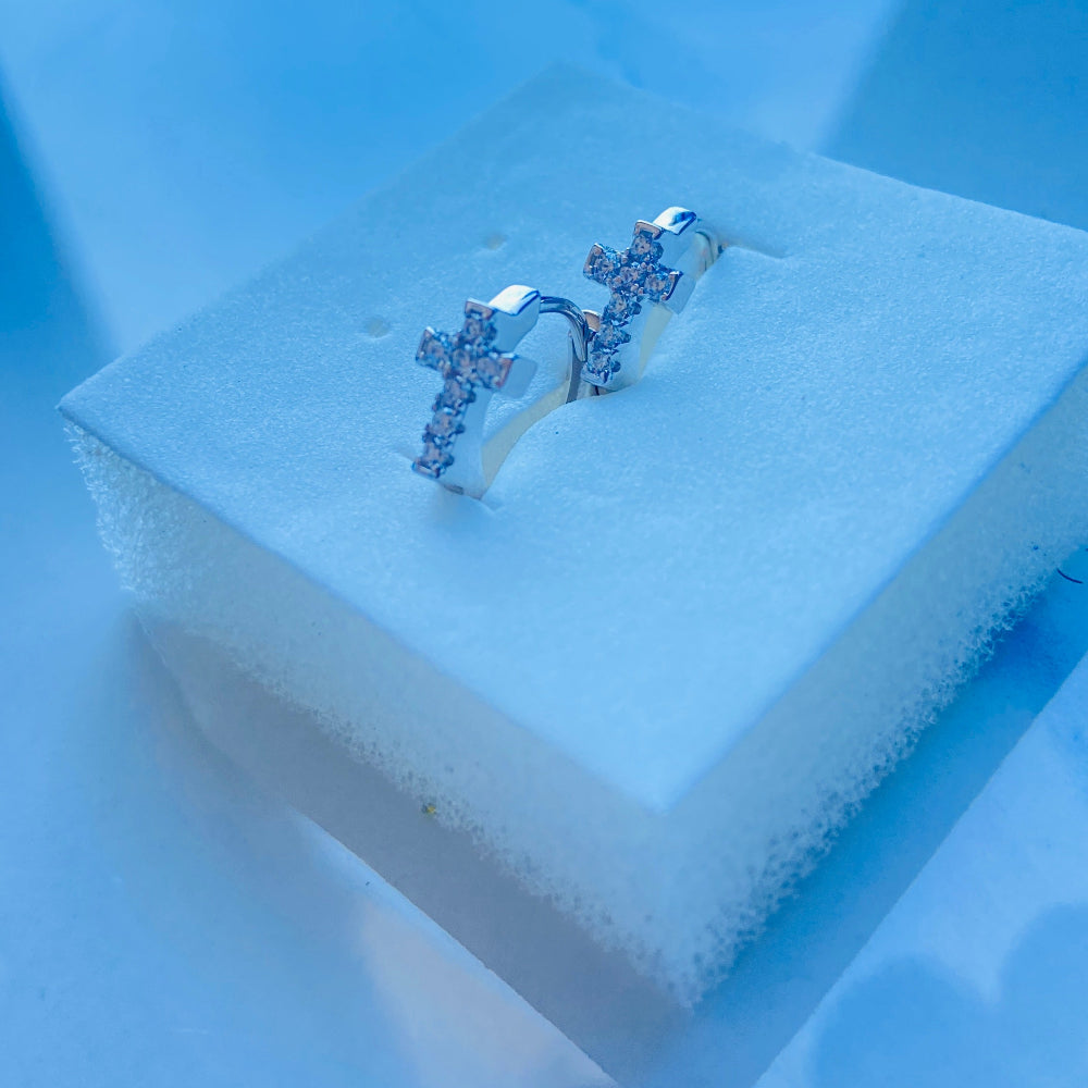 Silver cross-shaped earring on a white stand with a blue background white gold/silver crossed ice earrings cubic zirconia diamonds sleeper hoop Deep Shine Jewellers Jewellers jewelry DSJ. exclusive affordable jewellery Your Time To Shine 925 silver sterling silver 