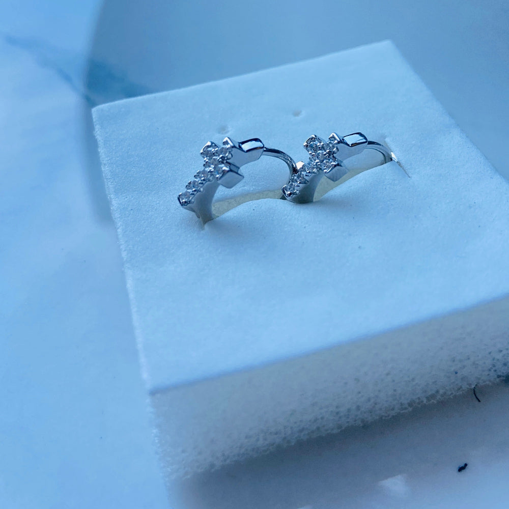 Silver earrings on a white jewelry display box with a blurred background white gold/silver crossed ice earrings cubic zirconia diamonds sleeper hoop Deep Shine Jewellers Jewellers jewelry DSJ. exclusive affordable jewellery Your Time To Shine 925 silver sterling silver 