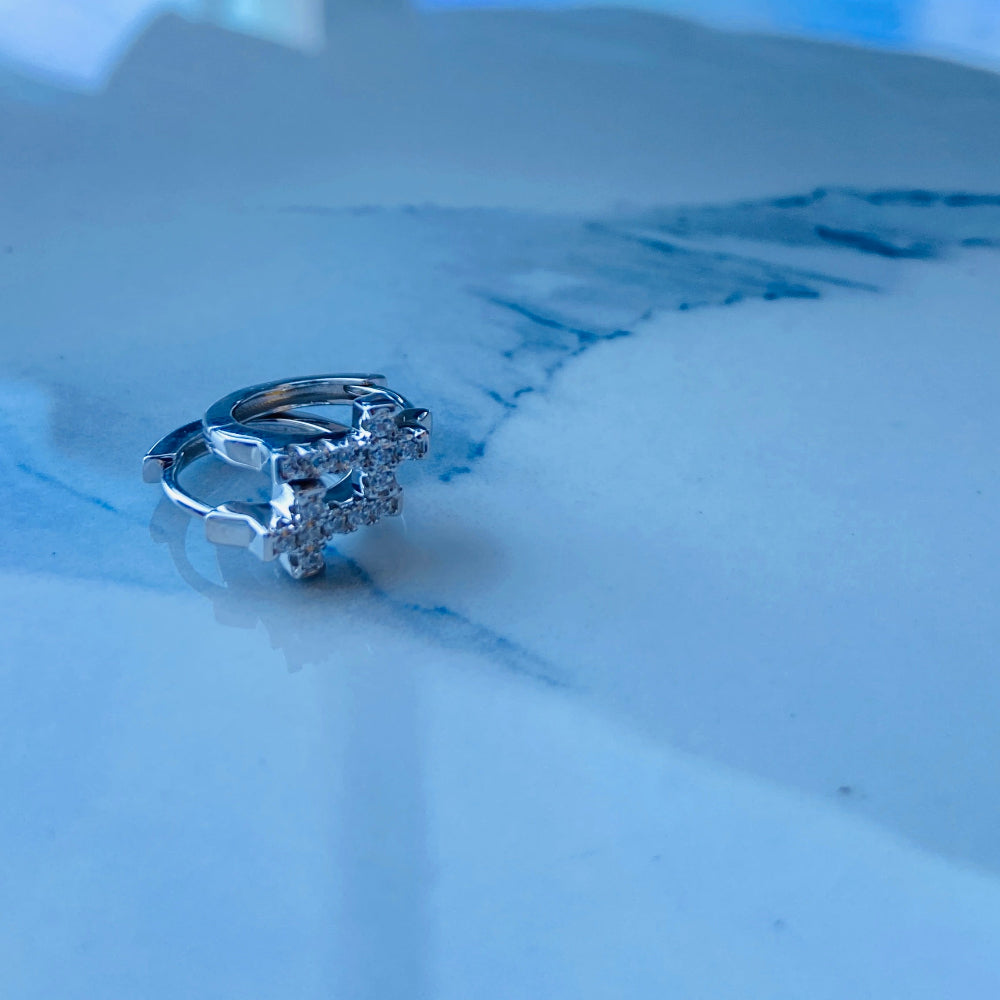 Silver ring with a large diamond on a white marble surface white gold/silver crossed ice earrings cubic zirconia diamonds sleeper hoop Deep Shine Jewellers Jewellers jewelry DSJ. exclusive affordable jewellery Your Time To Shine 925 silver sterling silver 