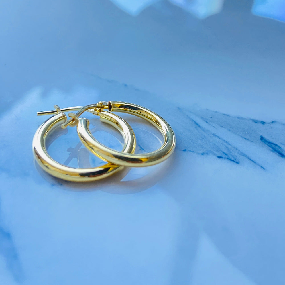 Gold hoop earrings on a light blue surface Gold silver sleepers for mens women kings queens man lady kingdom exclusive by Deep Shine Jewellers jewellery jewelry affordable luxury shinning DSJ Your Time To Shine Cape town craftsmanship 