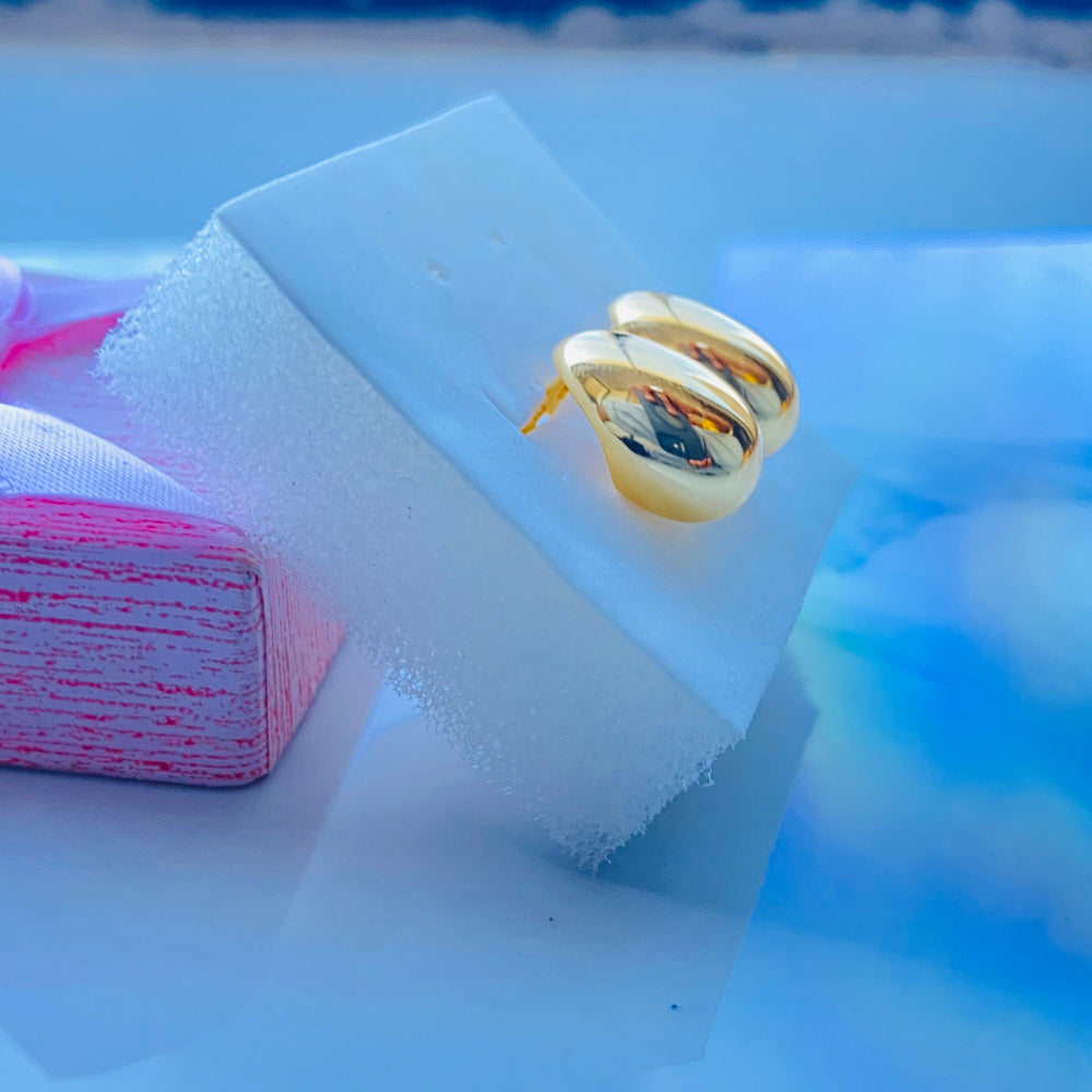 Gold spiral earring on a white cube with a blurred background gold silver rain drop earrings for women ladies queens 925 silver sterling silver exclusive jewellery crafted jewelry kingdom of DSJ Deep Shine Jewellers Your Time To Shine gold plated shinning 