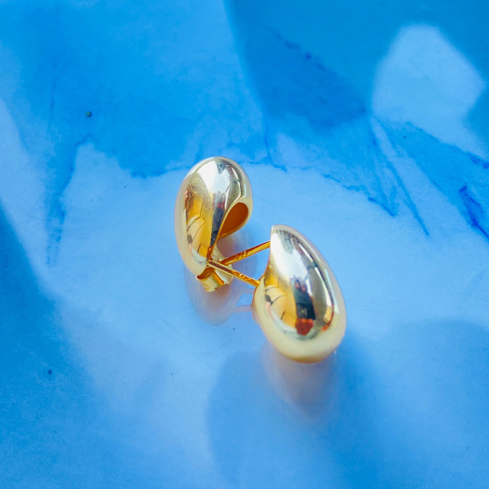 Gold earrings on a blue textured background gold silver rain drop earrings for women ladies queens 925 silver sterling silver exclusive jewellery crafted jewelry kingdom of DSJ Deep Shine Jewellers Your Time To Shine gold plated shinning 