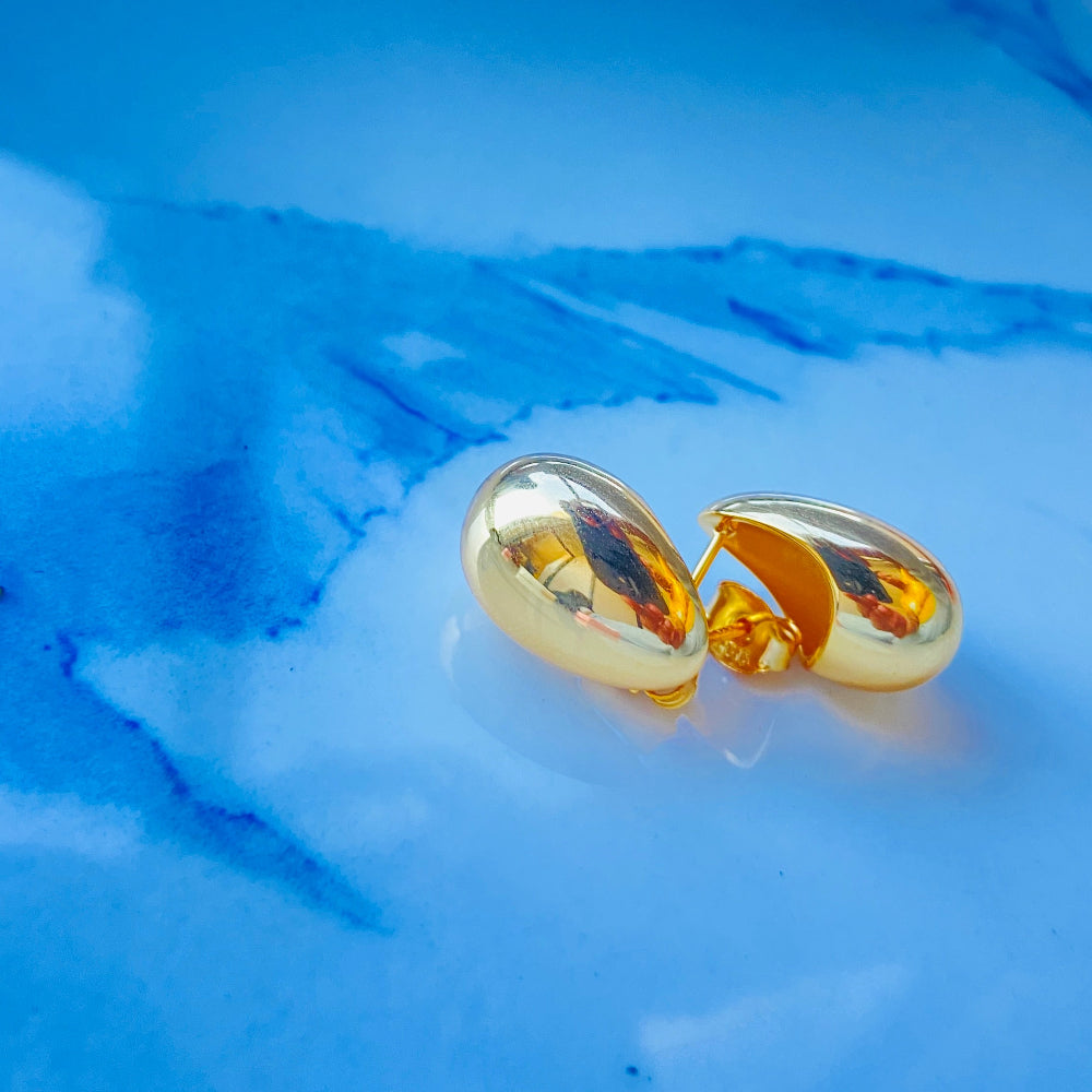 Gold earrings on a blue textured background gold silver rain drop earrings for women ladies queens 925 silver sterling silver exclusive jewellery crafted jewelry kingdom of DSJ Deep Shine Jewellers Your Time To Shine gold plated shinning 