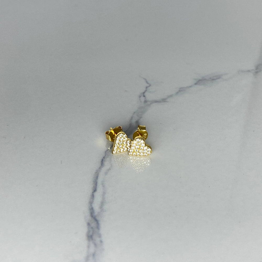 Heart-shaped gold earrings on a marble surface gold ice heart stud earrings gold plated golden 925 silver sterling silver exclusive craftsmanship premium jewellery jewelry affordable luxury best sellers trending christmas sale Deep Shine Jewellery DSJ Your Time To Shine online store diamond gemstones lab diamond cubic zirconia