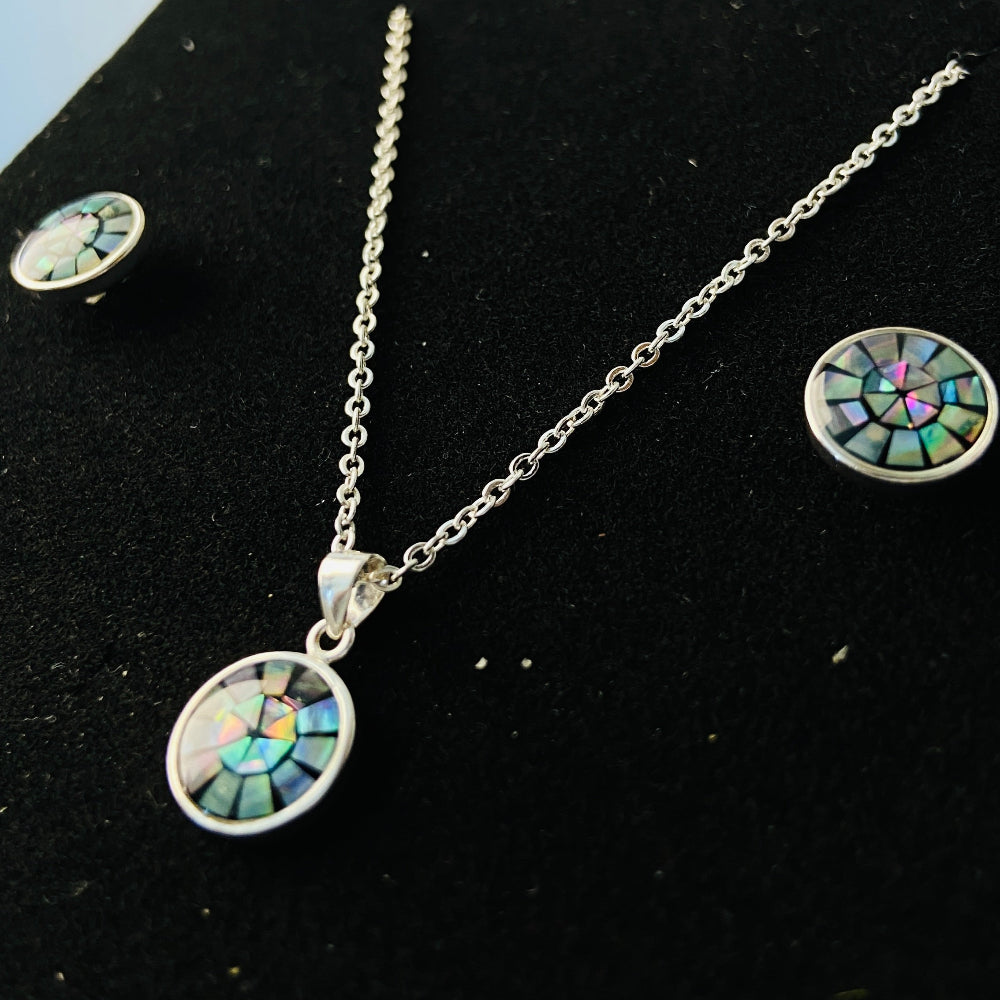 Silver necklace with pendant and matching earrings on a black stand. Two necklaces with round pendants on a marble surface silver paua necklace and earrings set chain women ladies queens 925 silver sterling silver exclusive craftsmanship elegance affordable luxury premium jewellery jewelry cape town artisans high quality best sellers trending Deep Shine Jewellers DSJ Your Time To Shine shop now kingdom Christmas sale 