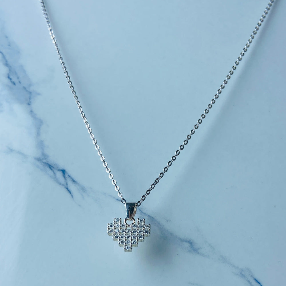 Silver necklace with a heart-shaped pendant on a marble surface Silver butterfly-shaped earrings on a marble surface Radiant Silver Pixelated Heart Necklace and Earrings Set by Deep Shine Jewellery women ladies queens 925 silver sterling silver cubic zirconia gemstone diamond lab diamond exclusive craftsmanship cape town artisans affordable luxury best seller trending christmas sale gift wishlish Your Time To Shine DSJ online store shop now 