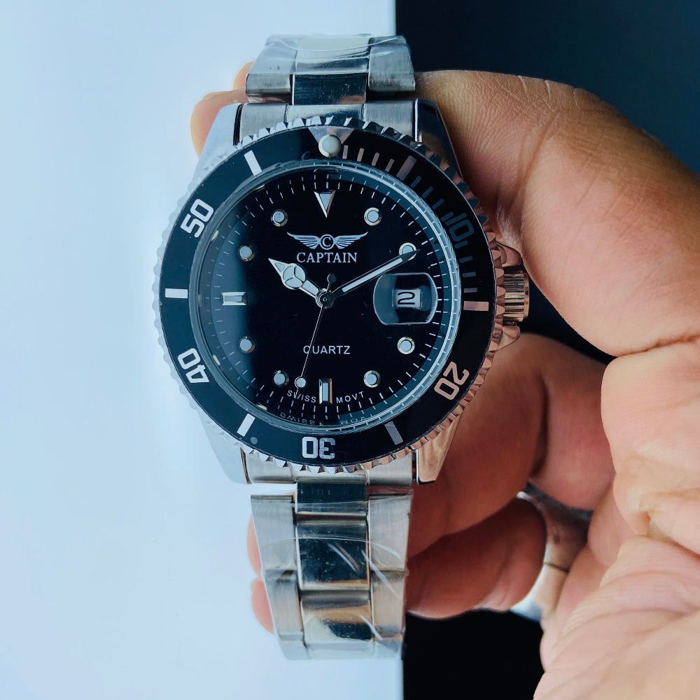 Hand holding a silver and black wristwatch against a light blue background Silver watch with black dial on a white surface captain mens watch black dial stainless steel rotating bezel quartz movement swiss movement timepiece watches timeless elegance brand new polished watched sapphire crystal hour markings jewellery jewelry premium quality affordable luxury best sellers trending shop now Deep Shine Jewellers DSJ Your Time To Shine mens gents kings 