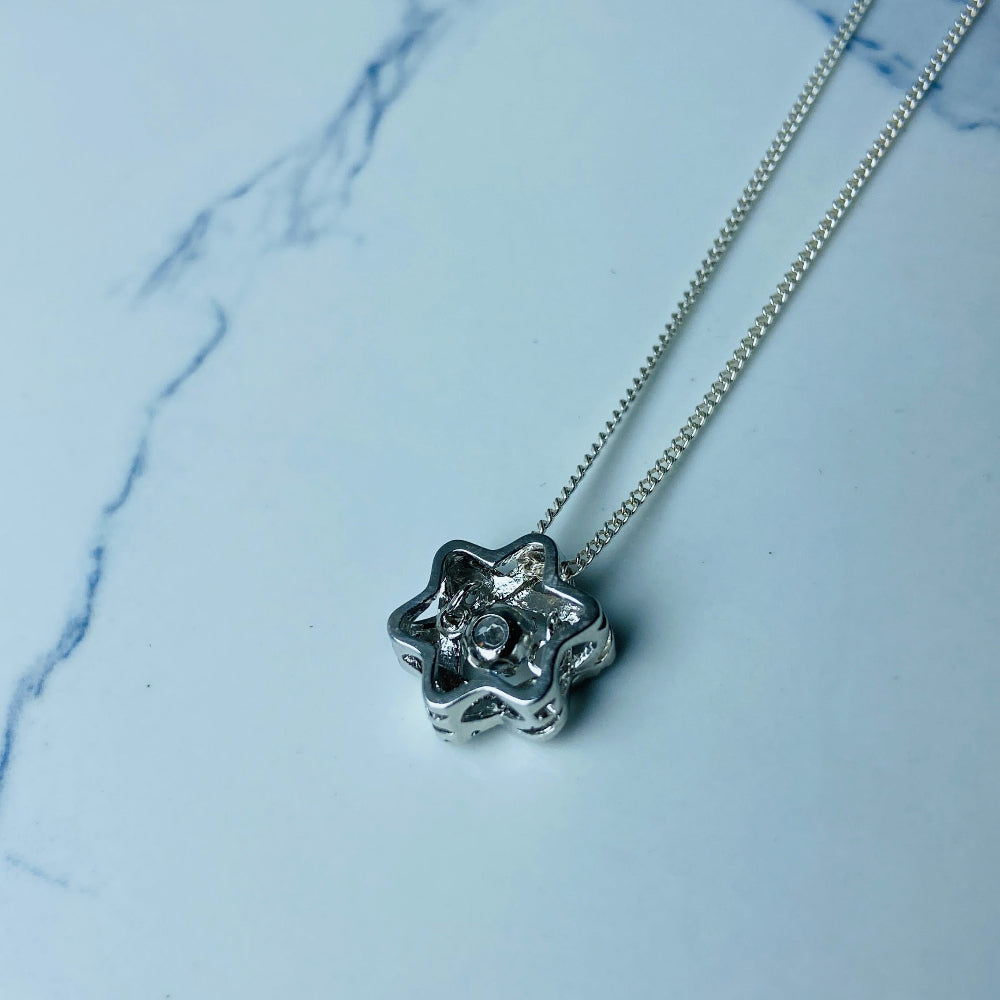 Silver necklace with a floral pendant on a marble surface Silver necklace with a floral pendant on a marble surface white gold silver dancing diamond pendant necklace chain diamond cubic zirconia gemstone lab diamond exclusive craftsmanship affordable luxury premium jewellery jewelry ladies women queens Deep Shine Jewellers DSJ Your Time To Shine best seller trending 925 silver sterling silver 