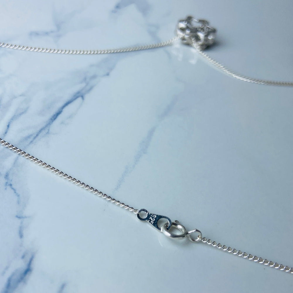 Silver necklace with a floral pendant on a marble surface Silver necklace with a floral pendant on a marble surface white gold silver dancing diamond pendant necklace chain diamond cubic zirconia gemstone lab diamond exclusive craftsmanship affordable luxury premium jewellery jewelry ladies women queens Deep Shine Jewellers DSJ Your Time To Shine best seller trending 925 silver sterling silver 