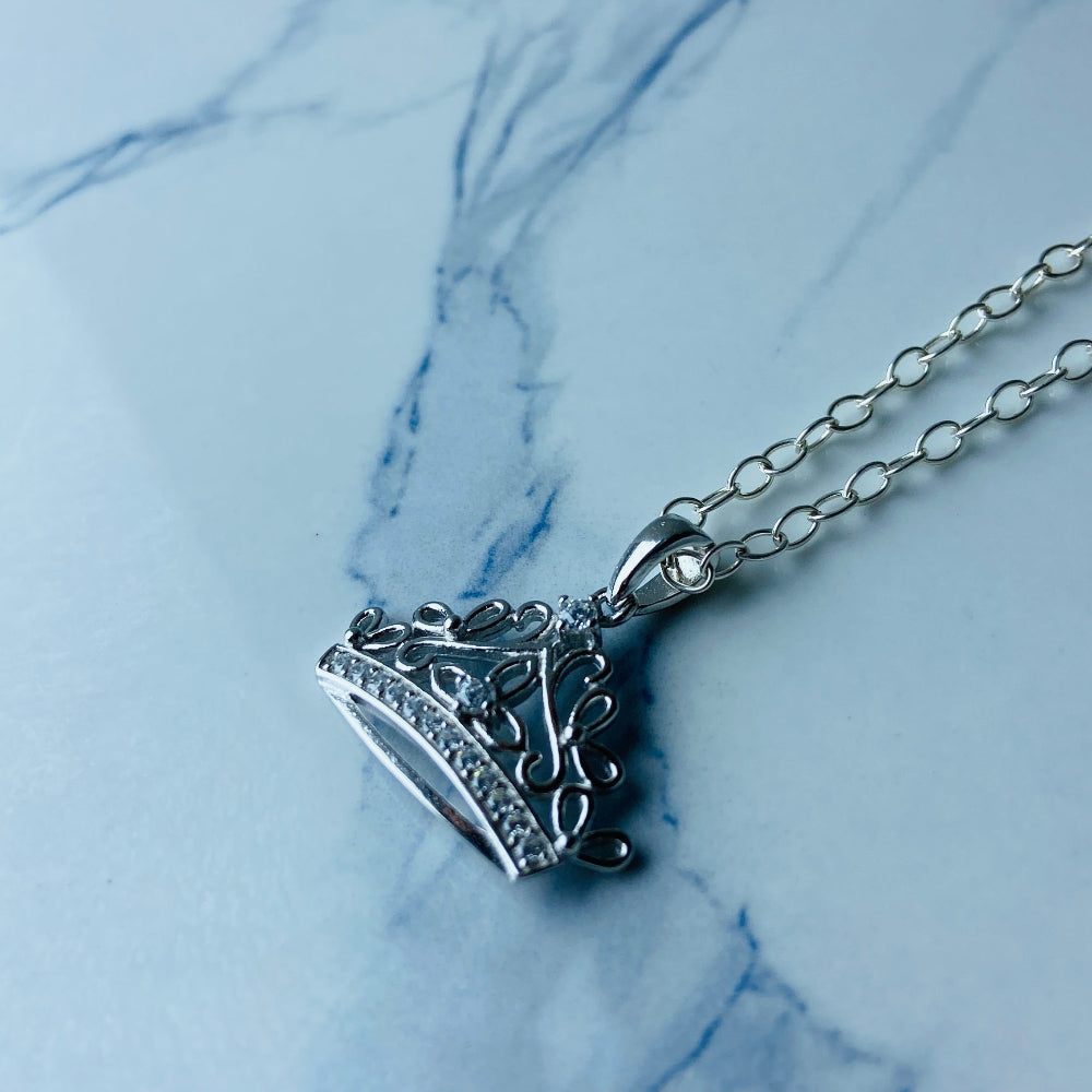 Silver necklace with a heart-shaped pendant on a marble surface Silver necklace with a detailed pendant on a marble background Silver necklace silver crown pendant necklace chain exclusive craftsmanship affordable luxury premium jewellery jewelry ladies women queens Deep Shine Jewellers DSJ Your Time To Shine best seller trending 925 silver sterling silver diamond lab diamond gemstones cubic zirconia Christmas special sale festive season holidays gift loved ones cable chain