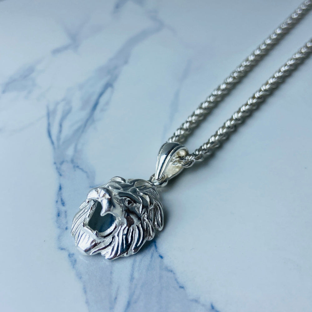 Silver lion head pendant on a chain against a marble background Silver Lions head pendant necklace marble surface pendant necklace curb chain exclusive craftsmanship affordable luxury premium jewellery jewelry ladies women queens kings mens gents Deep Shine Jewellers DSJ Your Time To Shine best seller trending 925 silver sterling silver cape town artisans christmas gifts present festive season holiday gifts for love ones