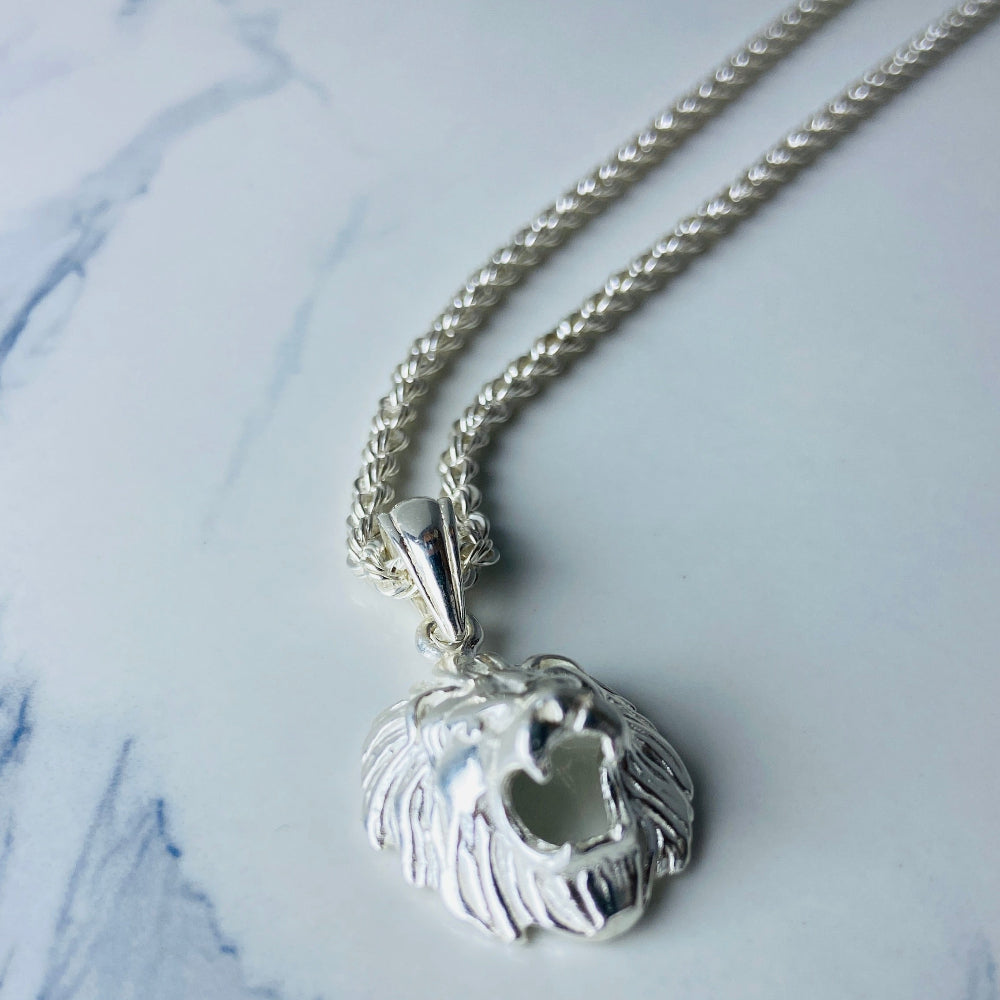 Silver necklace with a heart-shaped pendant on a marble surface Silver lion head pendant on a chain against a marble background Silver Lions head pendant necklace marble surface pendant necklace curb chain exclusive craftsmanship affordable luxury premium jewellery jewelry ladies women queens kings mens gents Deep Shine Jewellers DSJ Your Time To Shine best seller trending 925 silver sterling silver cape town artisans christmas gifts present festive season holiday gifts for love ones