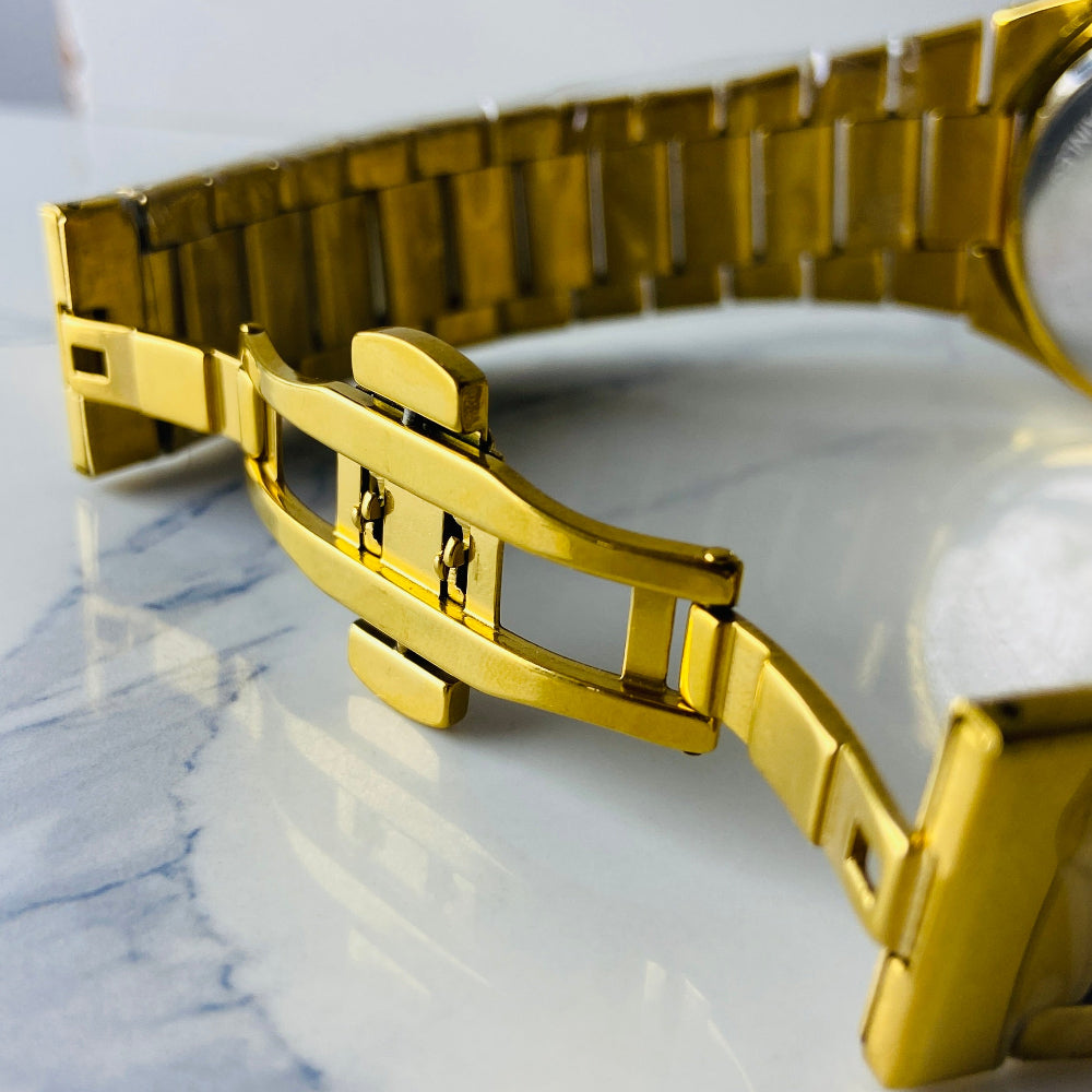 Gold watch band on a marble surface Gold watch with black face on a white marble surface gold MX mens watch gold plated stainless steel watches timepiece timeless luxury best seller trending Deep Shine Jewellers DSJ Your Time To Shine quartz movement black dial gold stick markers 36mm gold bezel 