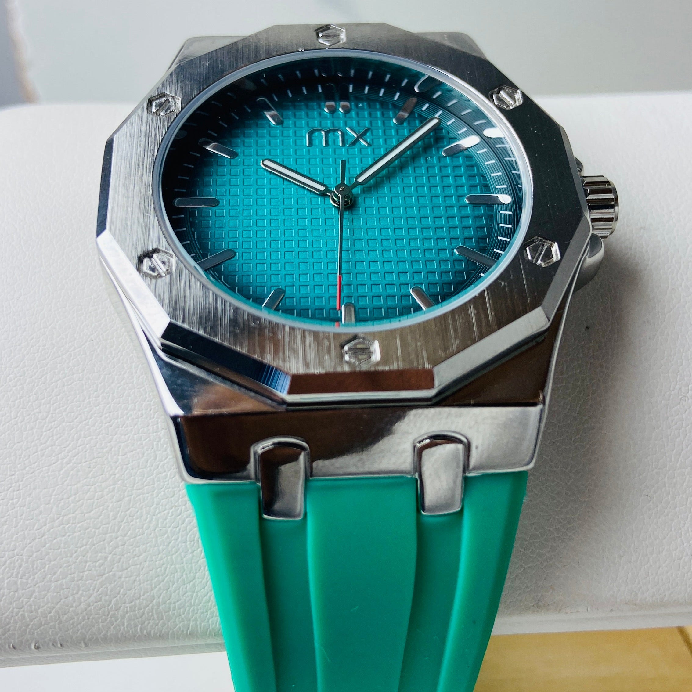 Turquoise watch with silver accents held against a light blue background Wristwatch with green strap and blue face on a white background silver watch with black and blue face on a white marble surface MX mens watch stainless steel watches timepiece timeless luxury best seller trending Deep Shine Jewellers DSJ Your Time To Shine quartz movement black dial gold stick markers 36mm gold bezel rubber strap green christmas sale xmas present holiday season festive season 