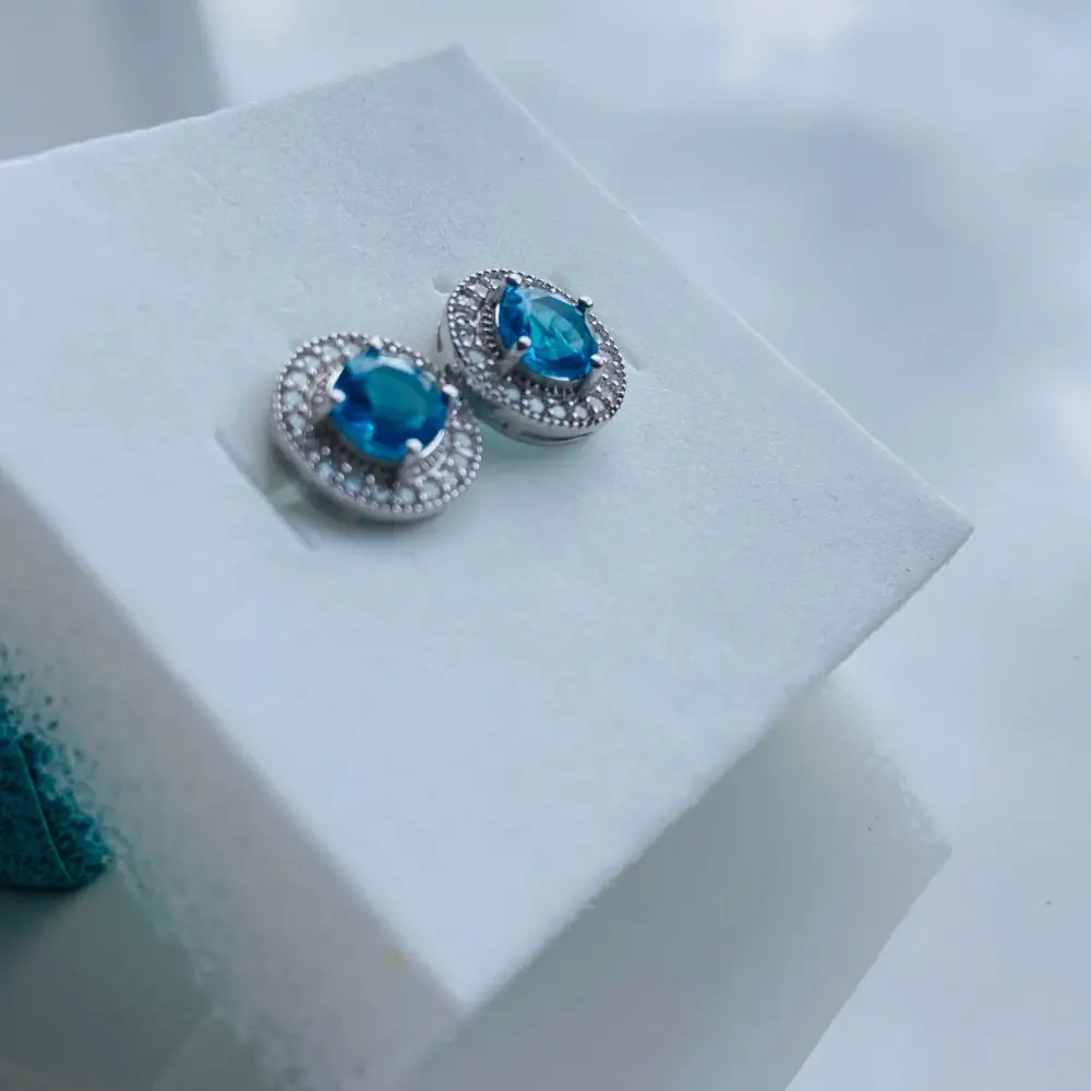Aqua Radiance white gold silver earrings with oval blue gemstones and white halo stones