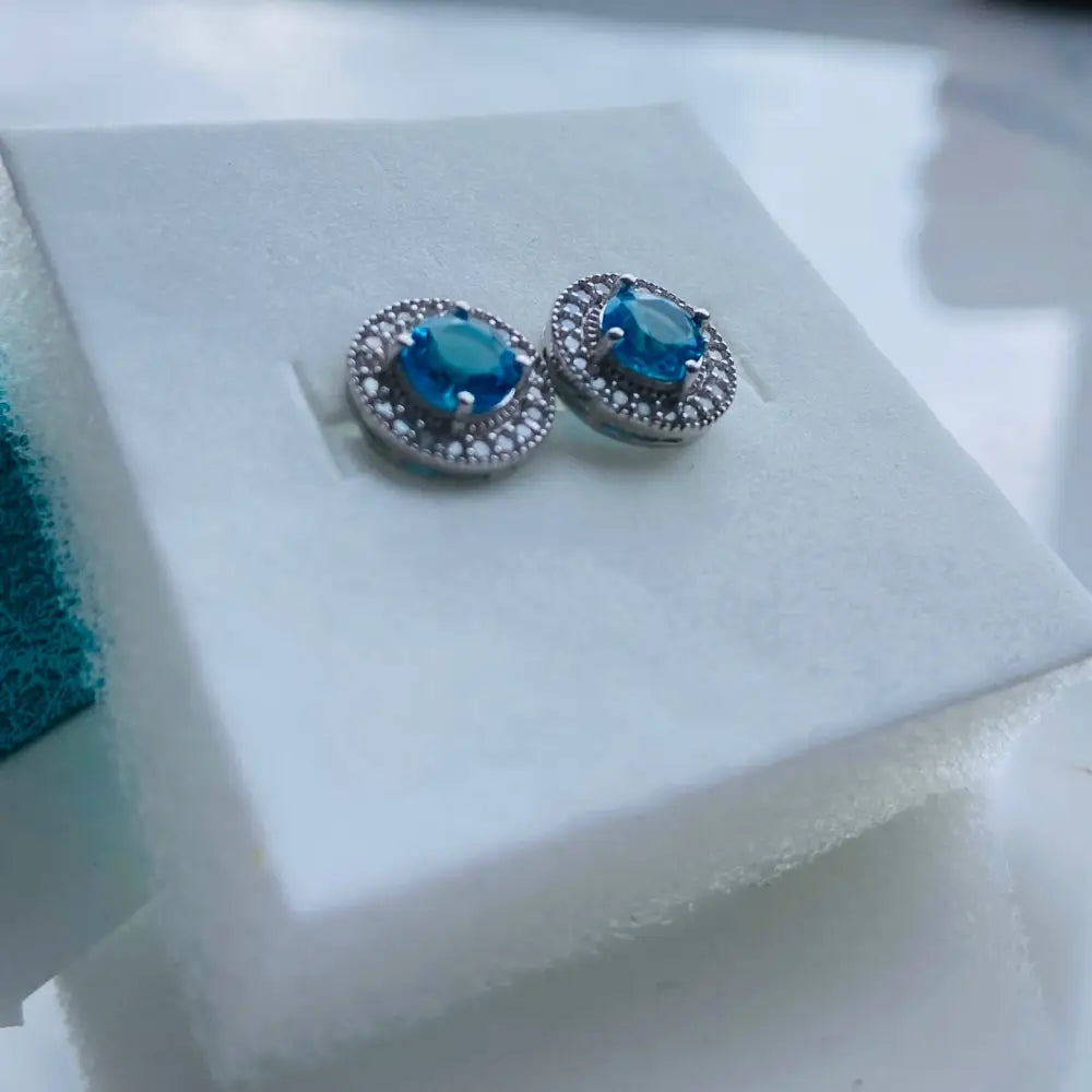 Silver stud earrings with teal gemstone and clear stones in white gold silver finish