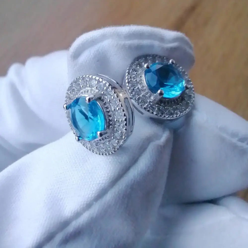 White gold silver earrings featuring vibrant blue gemstone and clear accent stones