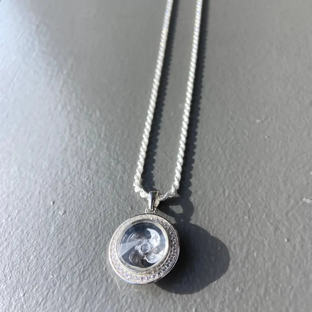 Silver flooded spinning necklace with round clear locket and gemstone accents