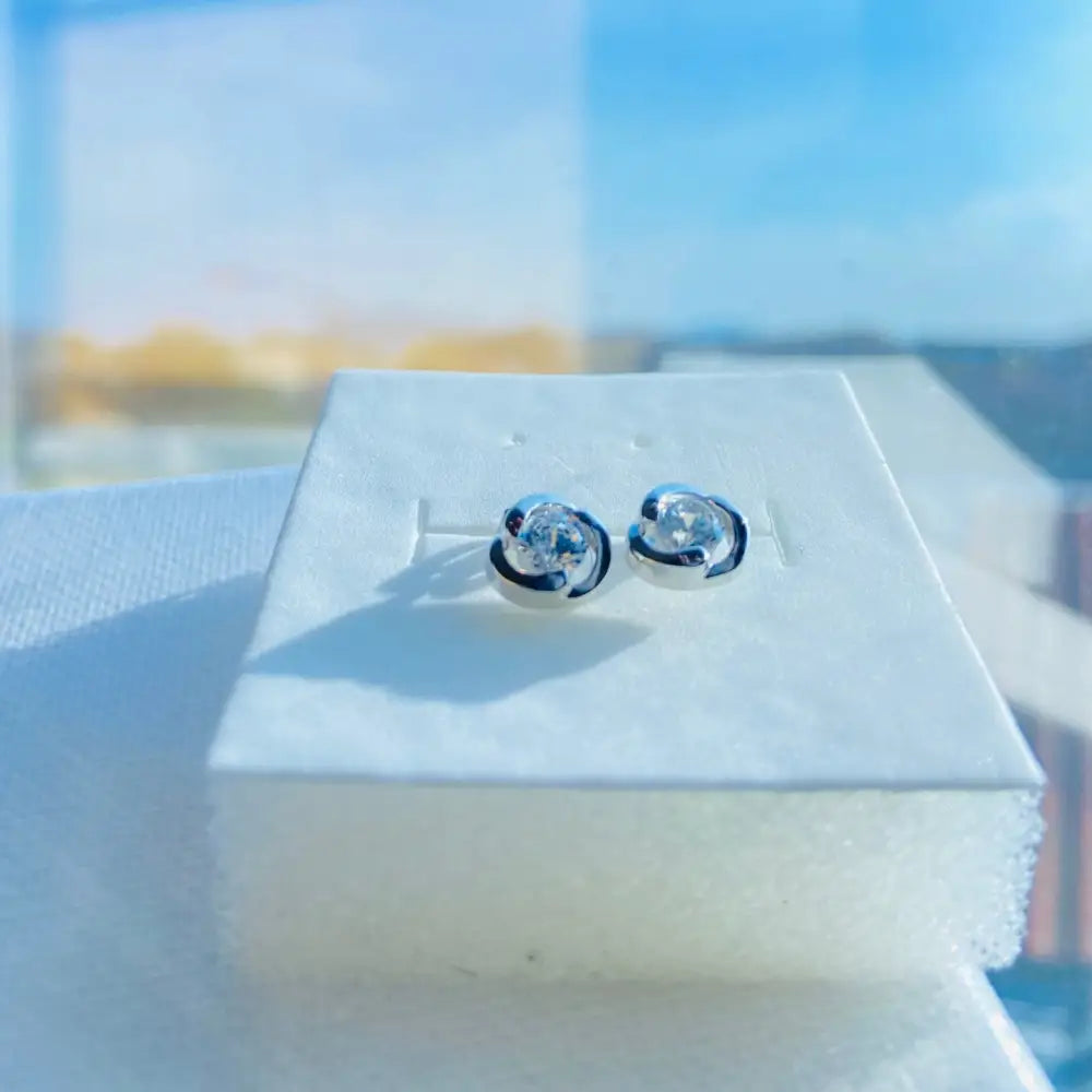 Silver rose stud earrings with central clear gemstones in deep shine white gold silver design