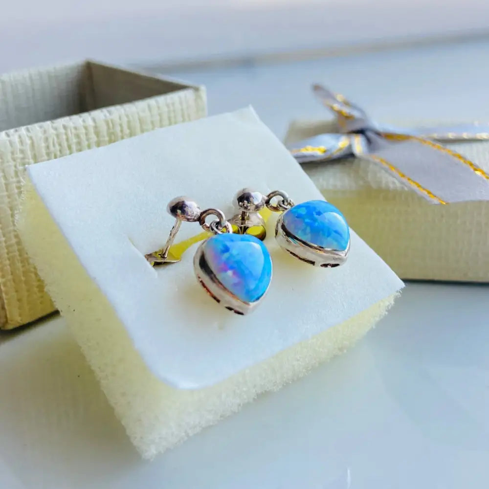 Silver earrings featuring heart opals in a set, displayed on white foam in gift box