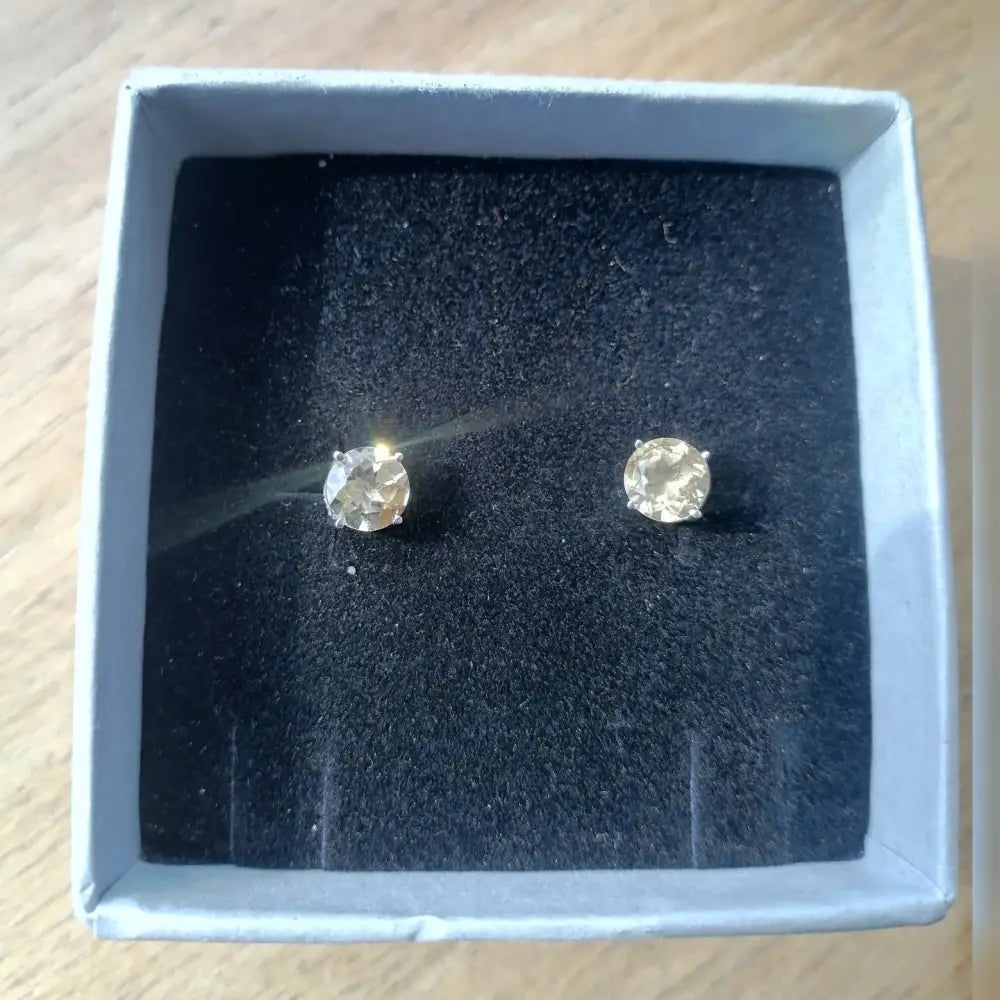 Round-cut diamond stud earrings in white gold silver claw setting in a jewelry box