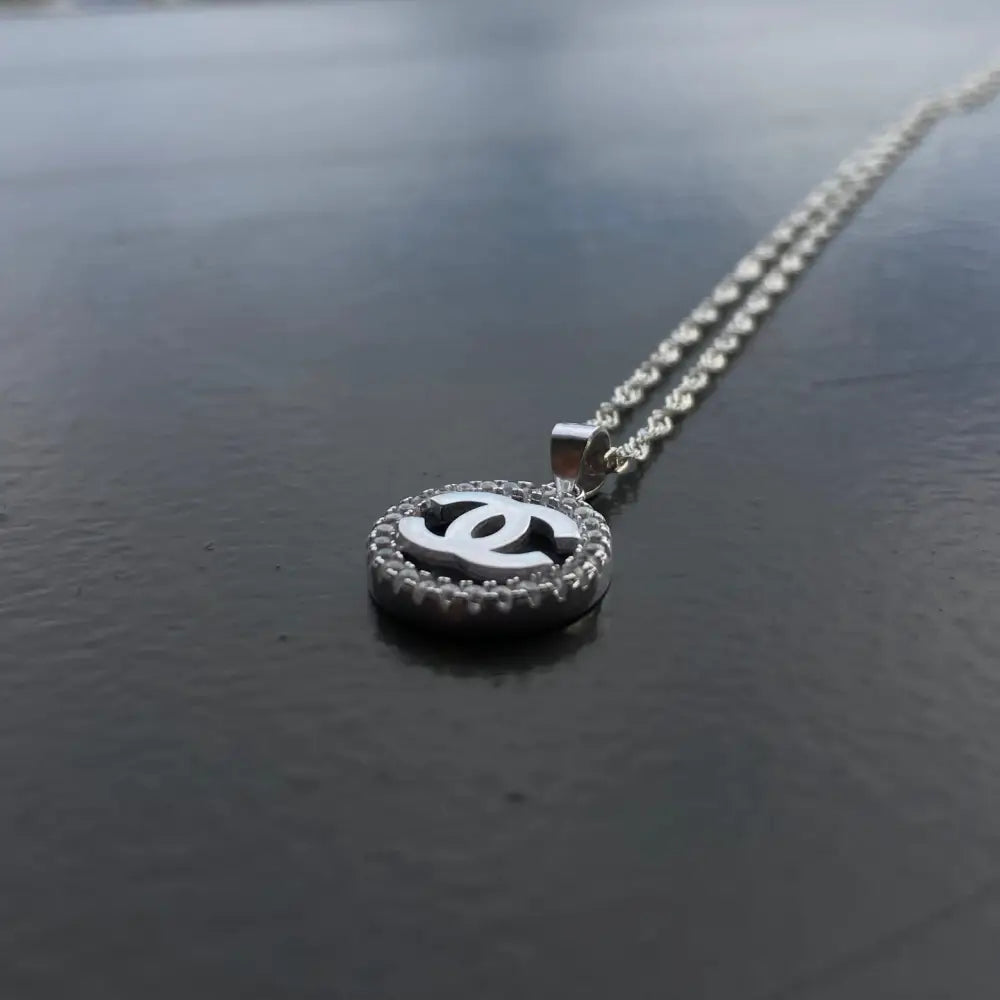 Silver Chanel necklace with circular encrusted pendant featuring interlocking C’s for timeless elegance