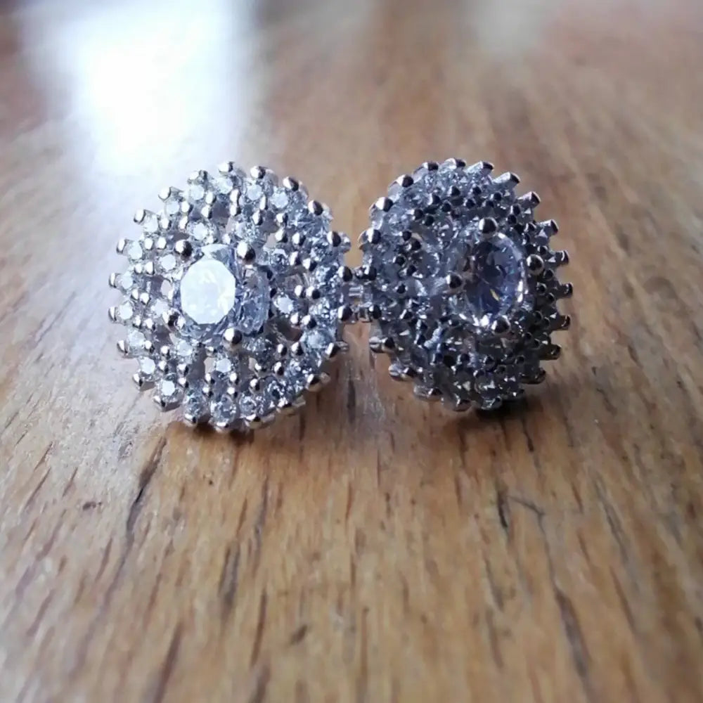 Sparkling white gold silver stud earrings with central clear gemstones and surrounding accents