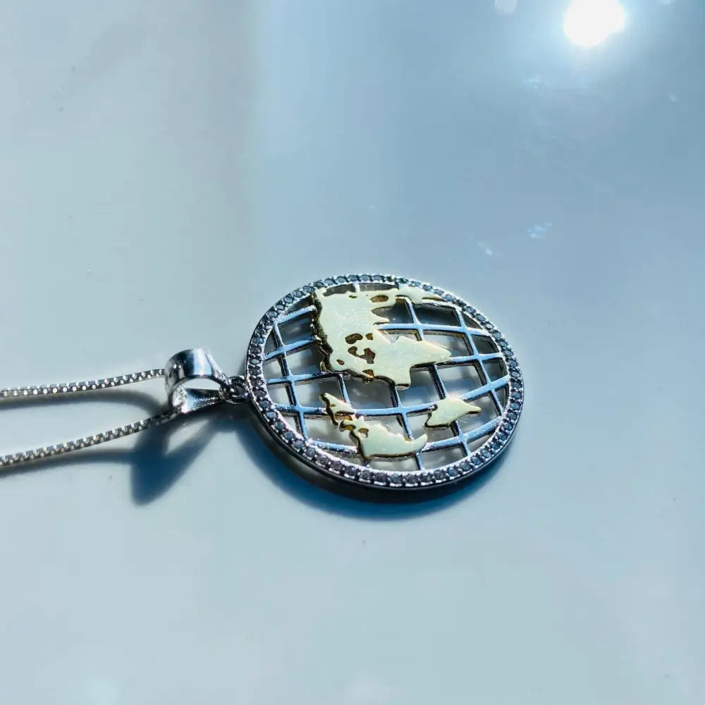 Silver world globe pendant with gold accents and pave-set diamond border for elegant jewelry. jewellery silver jewellery. Deep Shine Jewellers