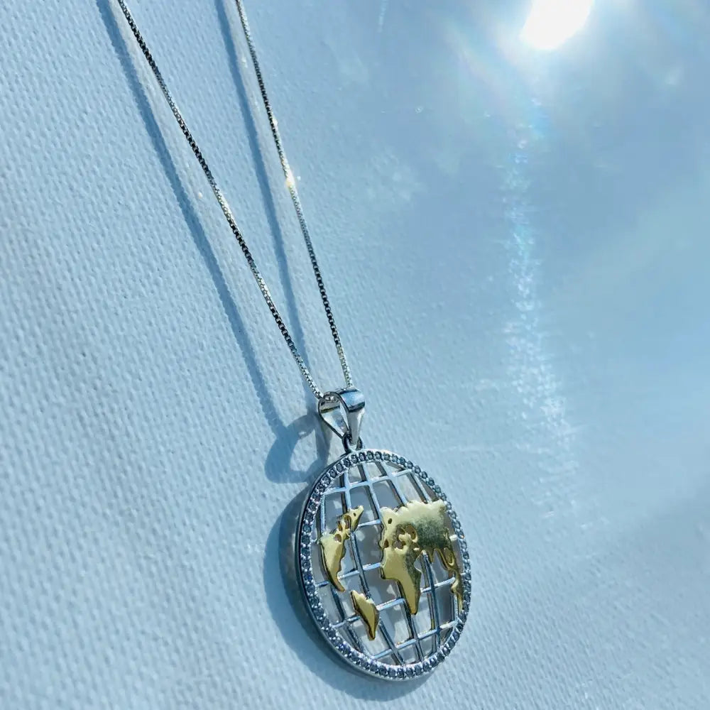 Silver world globe necklace with gold landmasses and sparkling stones around the rim. jewellery silver jewellery. Deep Shine Jewellers