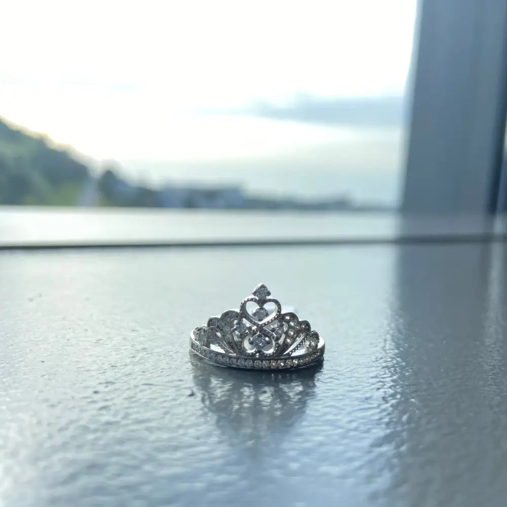 Silver-colored queen crown ring with heart and scrollwork design and clear stones