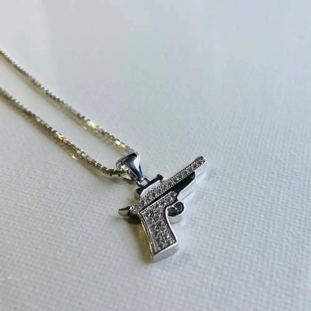 Silver-colored chain necklace with rhinestone-studded silver pistol pendant in white gold silver style